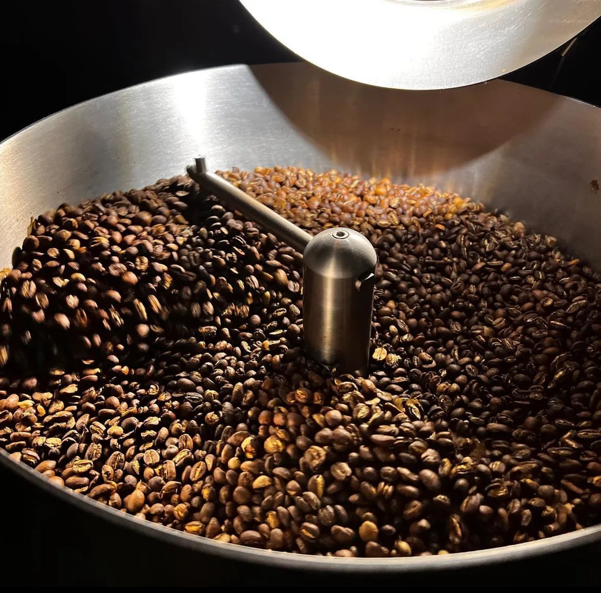 Freshly roasted coffee beans turning in the drum of the Black Honey roaster in Edinburg, Texas